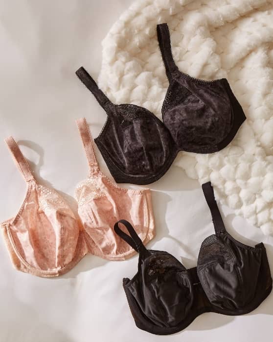 Three bras are displayed on a soft white surface with a textured blanket in the background.