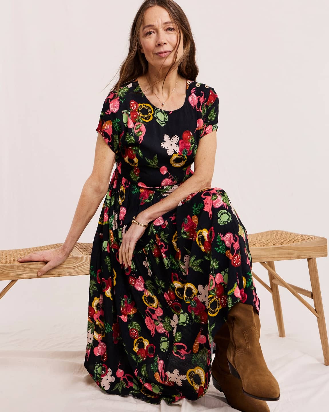 A model sat on a bench seat wearing a Julipa midi dress in navy print