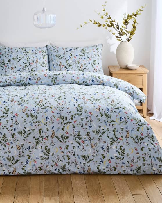 A double bed with a blue summer meadow duvet cover set