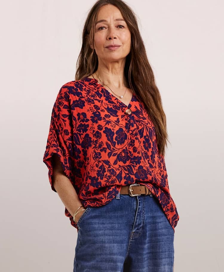 Model wearing a Julipa crinkle short sleeve top with a rust-coloured print, and blue jeans.