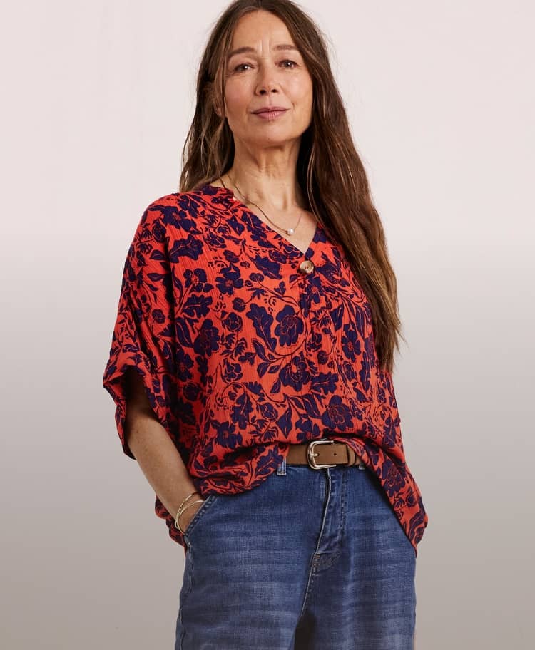 Model wearing a Julipa crinkle short sleeve top with a rust-coloured print, and blue jeans.
