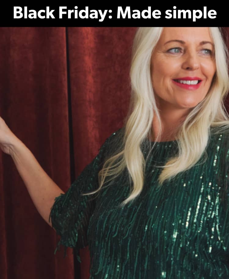 A person wearing a dark green, sequinned fringe dress is standing in front of deep red velvet curtains.