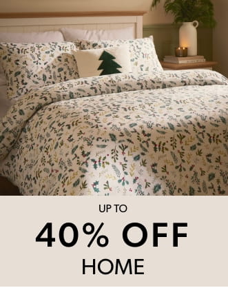 A neatly made bed with white bedding featuring a festive green and red botanical pattern.
