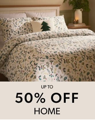 A neatly made bed with white bedding featuring a festive green and red botanical pattern.