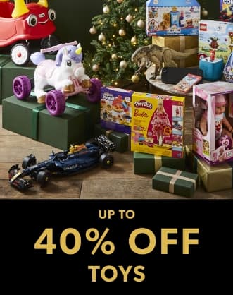 A festive display of toys including Play-Doh Barbie, LEGO sets, and a doll set, with a decorated Christmas tree in the background.